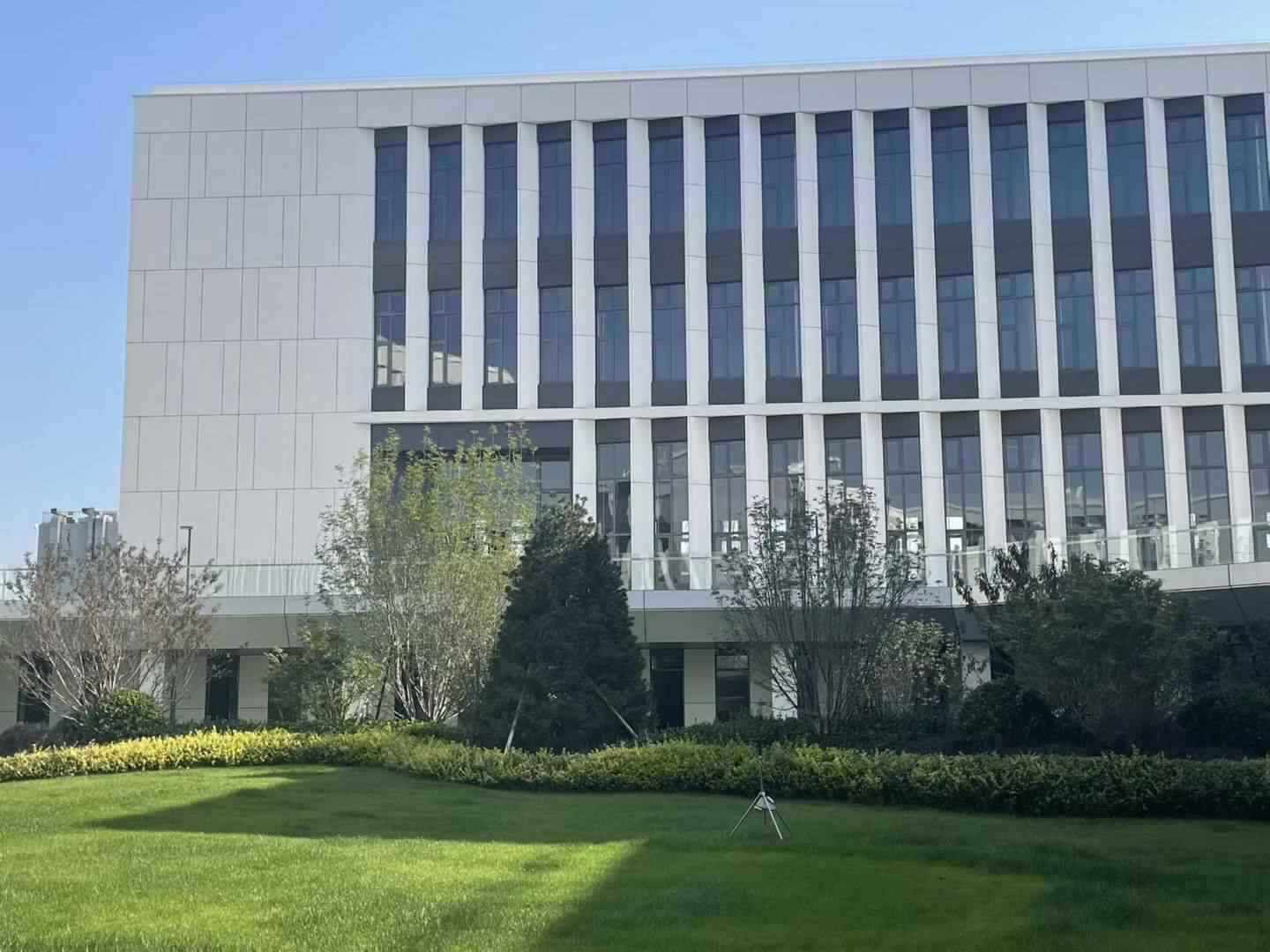 园区实景：多层独栋建筑与楼前集中绿地，立面简洁、采光面充足