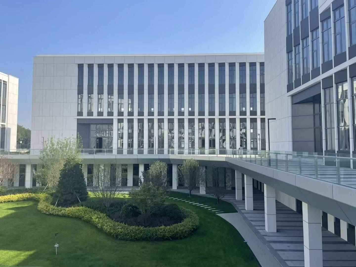 项目沿街实景：园区主入口方向建筑立面，周边为基地成型路网